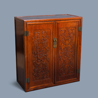 A Chinese wooden two-door cupboard with carved floral panels, 19th C.